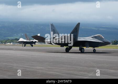 F-22 Raptors, betrieben von Mitgliedern der 199. und 19. Jagdgeschwader, Taxi während einer Trainingsübung 4. März 2022, auf dem Hilo International Airport, Hawaii. Ho`oikaika wurde von Total Force Airmen der Hawaii Air National Guard, der Nevada ANG und ihren aktiven Pendants aus dem 15. Wing und dem 354. Fighter Wing durchgeführt. Die Übung diente als Gelegenheit für Partner-Einheiten, ihre Fähigkeit zur schnellen Bereitstellung und zum schnellen Betrieb an Remote-Standorten zu demonstrieren und zu verbessern. (USA Foto der Air National Guard von Staff Sgt. John Linzmeier) Stockfoto